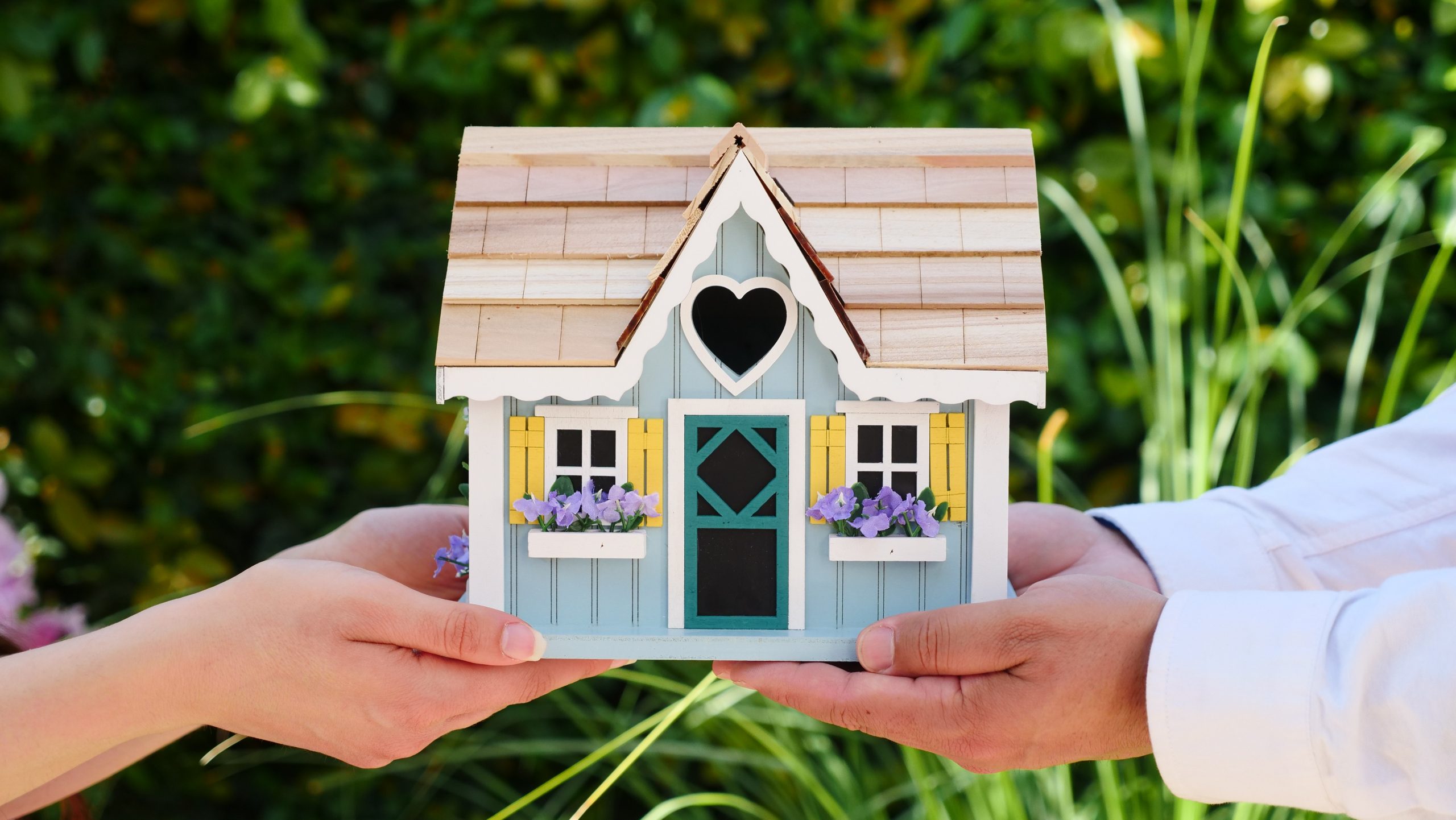 hands holding a miniature  house
